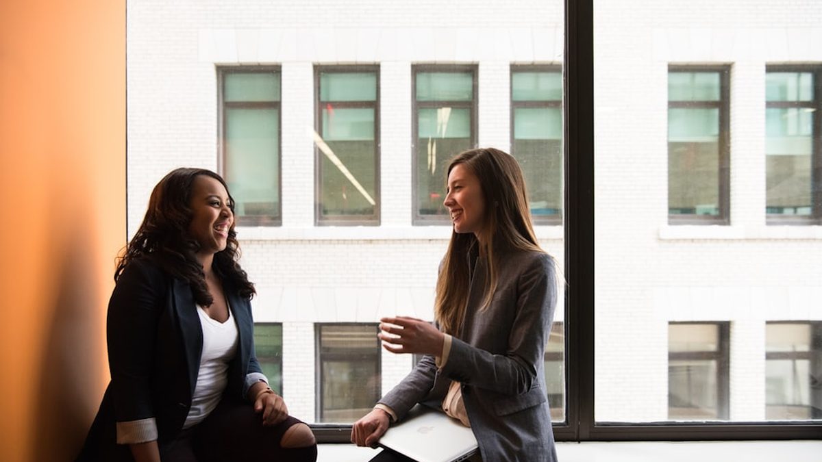 Dos personas conversando junto a una ventana en una oficina